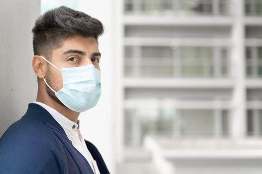 Portrait of a Handsome man in medical mask looking to camera at city. Handsome young man standing outdoors in medical mask. Coronavirus concept. High quality photo