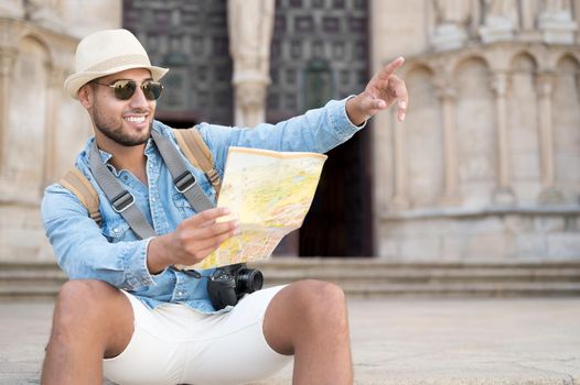 Handsome tourist man look at map while pointing finger in the direction of destination. Travel concept. Trip, backpacker tourist. High quality photo
