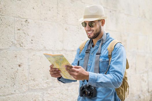 Young handsome man with tourist map looking around the city street. High quality photo.