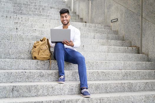 handsome young man working with laptop on stairs. High quality photo