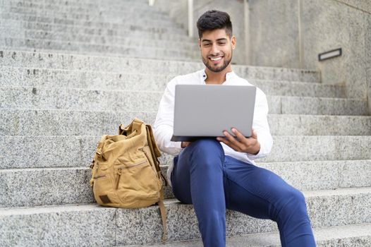 handsome young man working with laptop on stairs. High quality photo