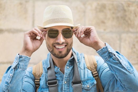 Stylish traveler bearded man in hat posing looking at camera, travel and wanderlust concept. High quality photo