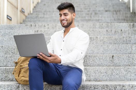 handsome young man working with laptop on stairs. High quality photo