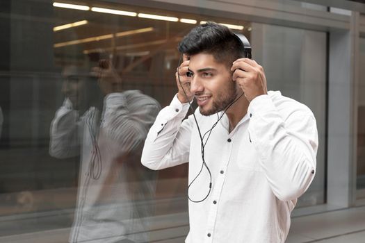 Handsome young man smiling and listening music on the street. High quality photo