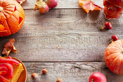 Halloween food still life abstract background with pumpkins, apples, cake, gummy worms, skull red drink and candles