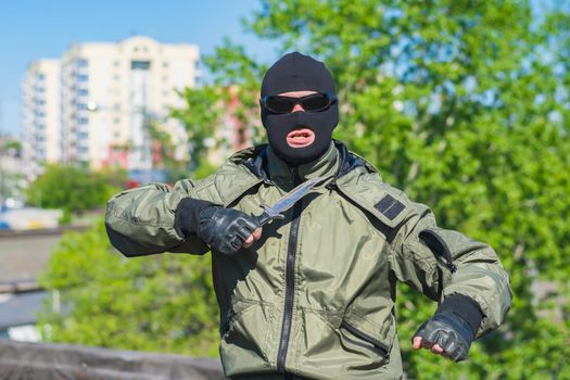 Street robber with a knife and a mask threatens and attacks people