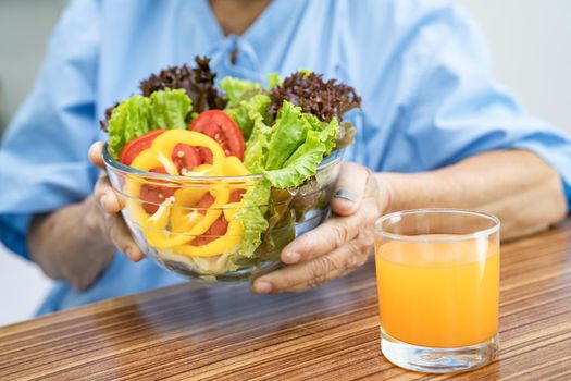 Asian senior or elderly old lady woman patient eating breakfast vegetable healthy food with hope and happy while sitting and hungry on bed in hospital.