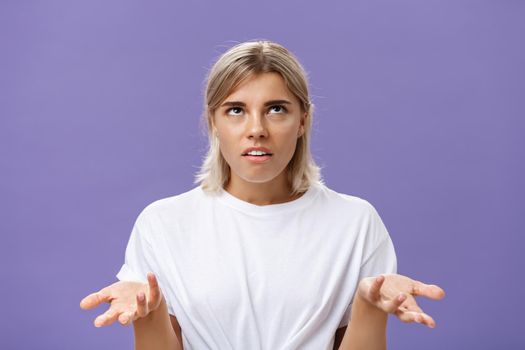 Nah I have no idea. Portrait of irritated bothered good-looking european woman with fair hair rolling eyes up with disappointed expression shrugging with hands raised in clueless gesture.