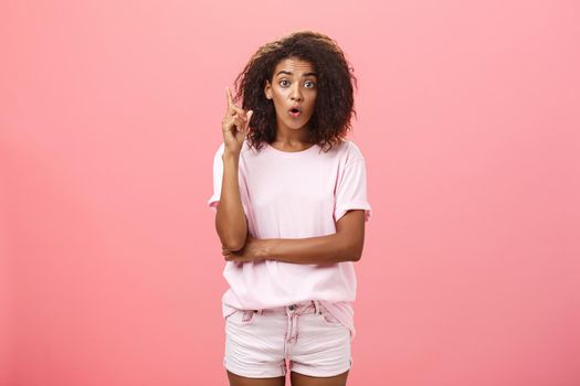 I got excellent idea listen. Portrait of excited charming and creative dark-skinned young woman with afro hairstyle in casual outfit raising index finger in eureka gesture and talking explaining plan. Body language concept