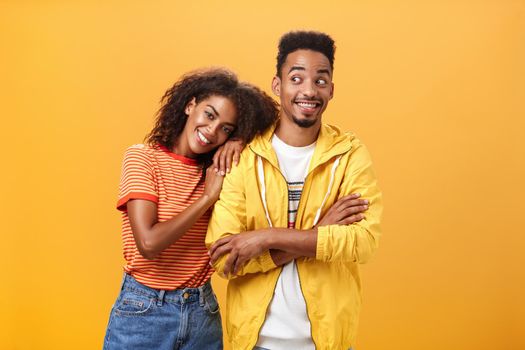 Guy feeling happy girl lean on his shoulder grinning and chuckling from happiness standing pleased and joyful over orange background while woman hugging best friend upbeat she can rely on him. Relationship concept