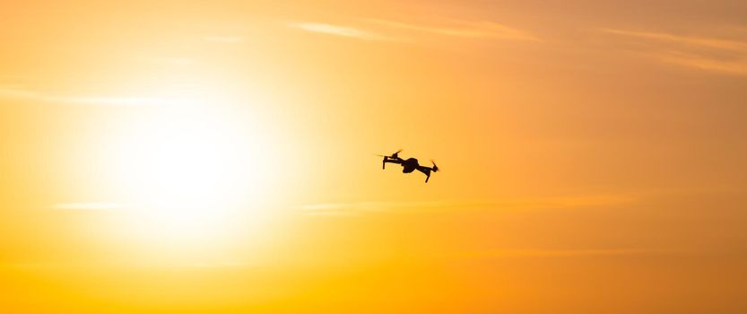 The drone is in flight at sunset . Video shooting from above. An article about the choice of a quadrocopter. Pros and cons of the drone. Sunset