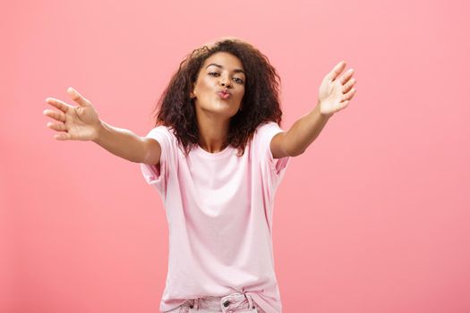 Come closer let me hug you. Portrait of passionate confident and happy good-looking african american woman with curly hairstyle folding lips pulling hands towards camera to cuddle and give kiss. Relationship and feelings econcept