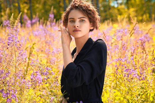 A beautiful young woman with a bouquet of lupine in her hand.Soft focus