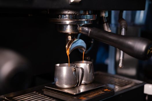 black coffee is pouring from professional coffee machine. coffee making by barista. dark loft coffee shop.