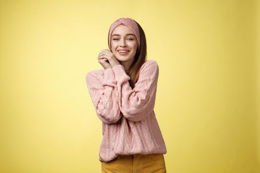 Cheerful glamour young pretty european female in pink cozy knitted headband, sweater leaning on hands pressing palms together silly seeing cute animal, feeling delight compassion, tender emotions.