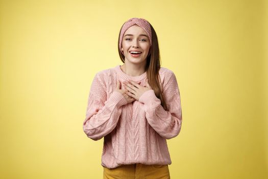Grateful delighted charming young 20s woman wearing sweater pressing arms to chest happily, thankful, expressing gratitude, heartfelt appreciating gesture smiling amused, in love with romantic gift.