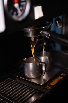 black coffee is pouring from professional coffee machine. coffee making by barista. dark loft coffee shop.