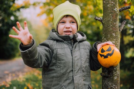 A boy with a Halloween pumpkin with eyes . The feast of fear. Halloween. An orange pumpkin with eyes. An article about Halloween.