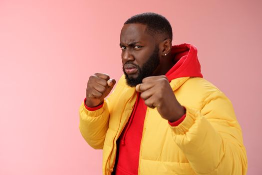 Serious-looking angry irritated young black bearded man pissed rude person attidude raise fists frowning grimacing anger furious feel punch face standing boxing pose wanna fight pink background.