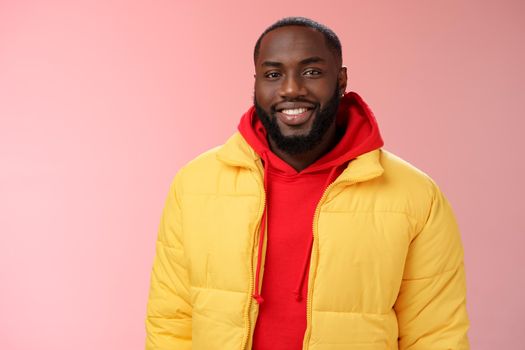 Waist-up happy charismatic good-looking bearded guy in yellow jacket red hoodie smiling joyfully white perfect smile talking have nice friendly conversation, standing pink background.