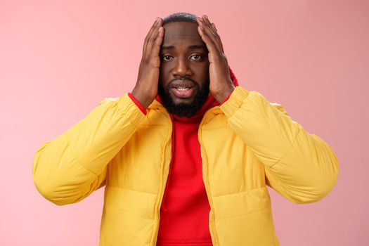 Shocked upset african-american bearded guy feel regret stunned hear terrible news hold hands head widen eyes stupor standing speechless troubled, look perplexed terribly sad, pink background.