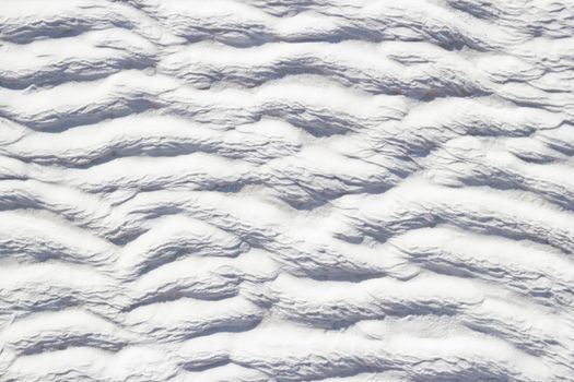 Texture of Pamukkale calcium travertine in Turkey, white pattern of horizontal waves, close-up.