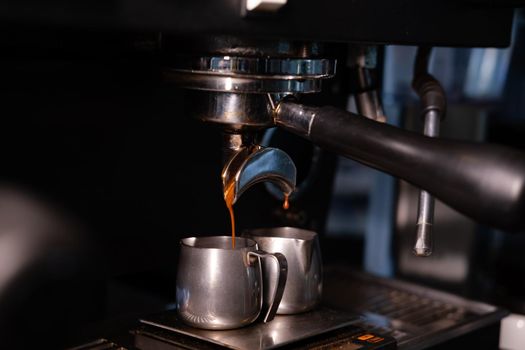 black coffee is pouring from professional coffee machine. coffee making by barista. dark loft coffee shop.