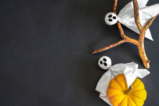 Two ghosts with pumpkin on black background. Copy space. Halloween symbols.