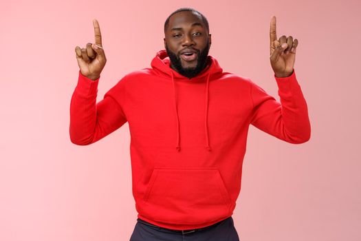 Arrogant young bragging handsome cheeky african-american bearded guy pointing raised index finger up smirking look assertive self-assured, recommending amazing product, pink background.