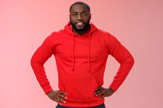 Helpful attractive friendly bearded african-american boyfriend wearing red hoodie hold hands waist smiling wanna help asking what do, lending hand, standing confident assertive pink background.