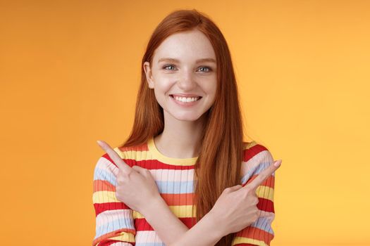Relaxed carefree confident young helpful redhead girl showing you choices pointing crossed arms left right different directions pick variants present lots opportunities, smiling orange background.