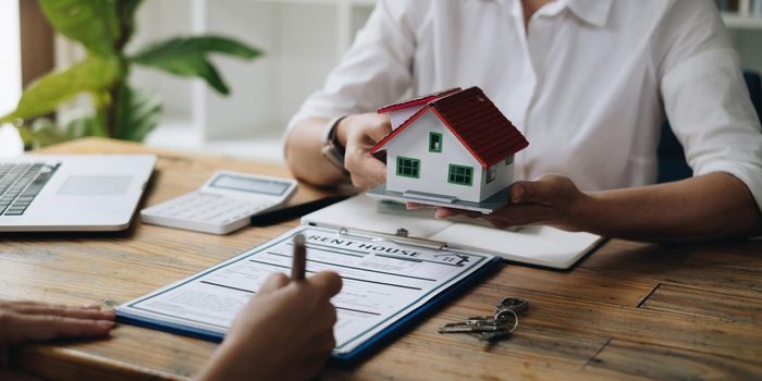 Close up of Business woman pointing and signing agreement for buying house. Bank manager and real estate concept