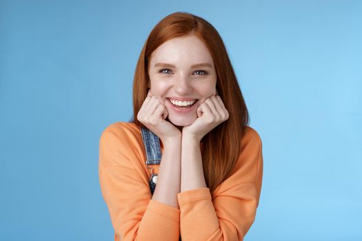 Lifestyle. Enthusiastic sassy good-looking redhead caucasian girl lean head palms look amused intrigued listen interesting story pleased smiling laughing silly jokes standing blue background excited happy.