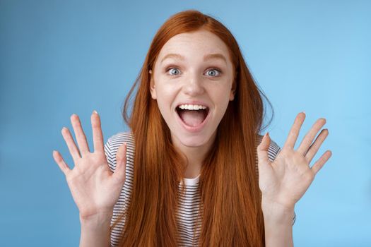 Excited charismatic happy lively redhead young funny woman smiling thrilled open mouth fascinated wide eyes surprised staring adore cool new product raise palms waving hello, show ten dozen.