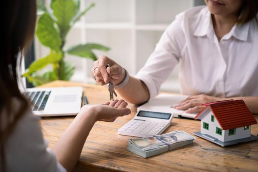 Close up of Business woman giving house key after signing agreement for buying house. Bank manager and real estate concept