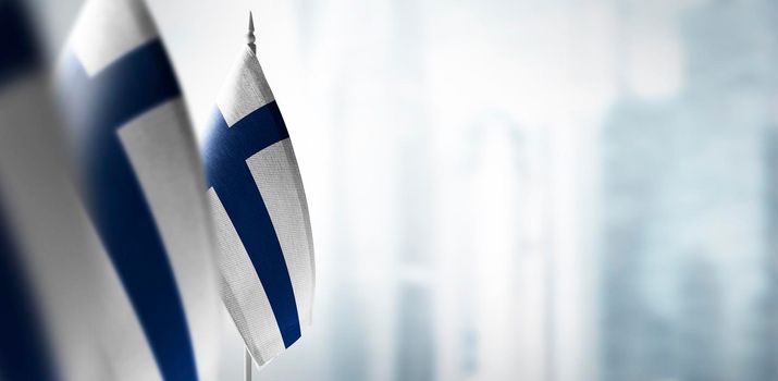 Small flags of Finland on a blurry background of the city.
