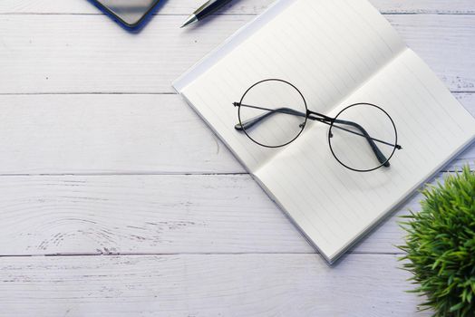 notepad, eyeglass and a pencil on wooden table .