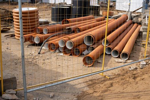 Plastic orange pipes lie on the ground at a construction site.