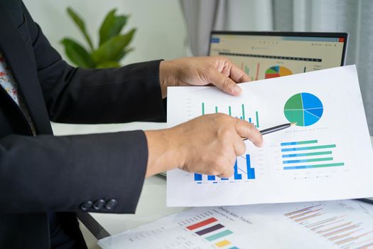 Asian accountant working and analyzing financial reports project accounting with chart graph in modern office, finance and business concept.