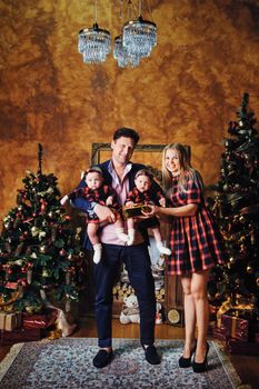 A happy big family with their children in the New Year's interior of the house by the fireplace next to the Christmas tree.