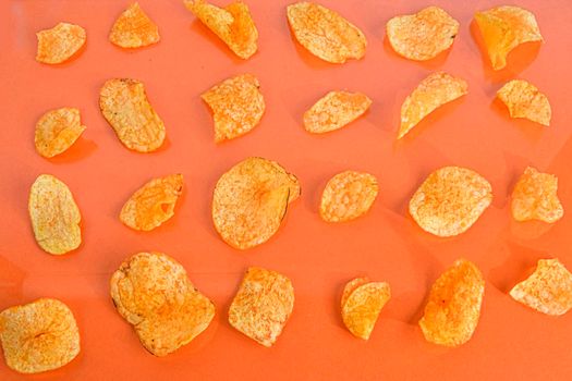 Potato chips or crisps on orange background. Movie background. Top view or flat lay. Potato chips on a pastel orange background, top view. Cinema Concept. Flat lay.