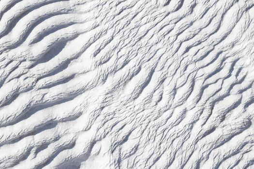 White abstract texture of Pamukkale calcium travertine in Turkey, asymmetric pattern close-up.