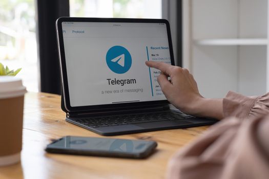 CHIANG MAI, THAILAND, SEP 29, 2021 : Woman pointing at ipad with social networking service Telegram on the screen. iPhone 10 was created and developed by the Apple inc