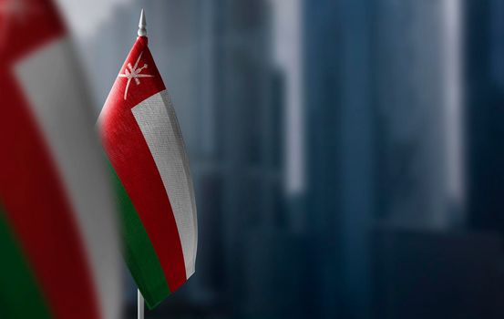 Small flags of Oman on a blurry background of the city.