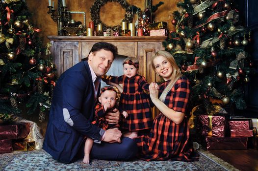 A happy big family with their children in the New Year's interior of the house by the fireplace next to the Christmas tree.