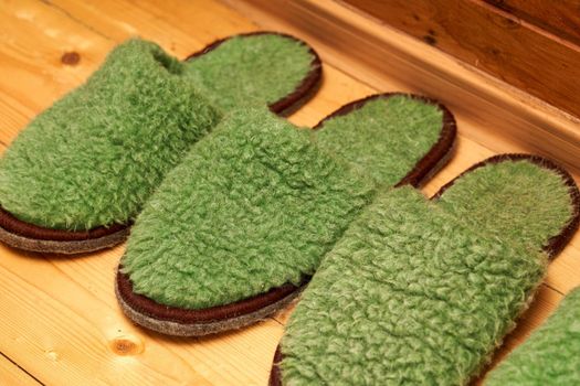 Felt green slippers for guests on the wooden floor in the hallway. Close up