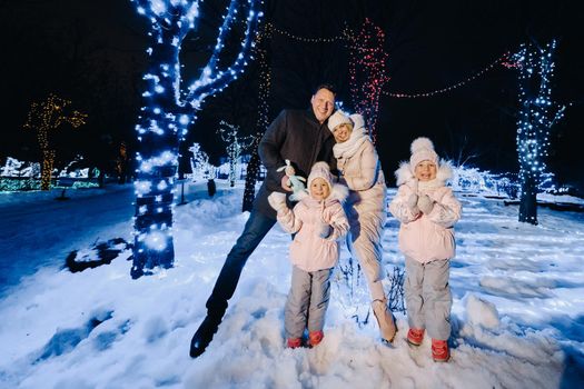 A large family with children in a Christmas city at night with night lights.