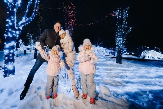 A large family with children in a Christmas city at night with night lights.