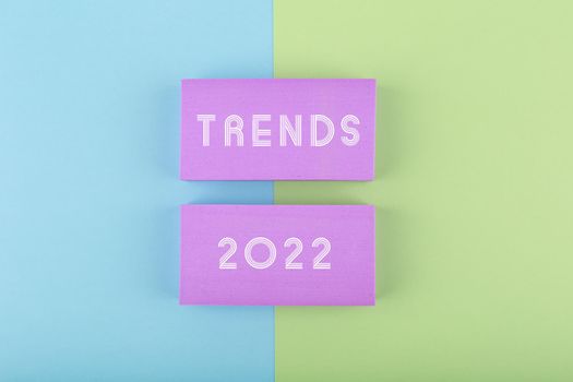 Trends 2022 written on purple rectangles on green and blue background. Concept of newest, latest, hot and popular trends of 2022