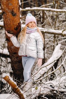 a little girl in a silver jacket in winter goes outside in winter.